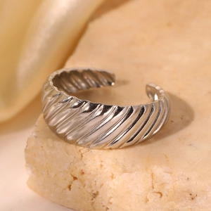 Détail macro d'une bague croissant argentée avec texture spirale sur un support pierre