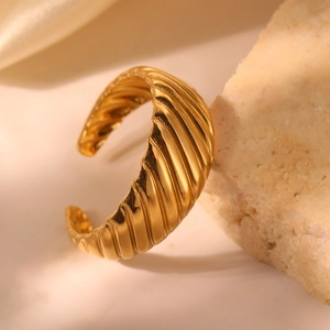 Bague croissant dorée minimaliste avec motif de vagues texturées sur fond de pierre chaude