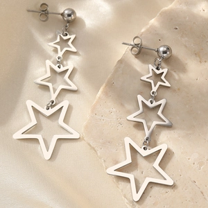 Elegant silver-tone stainless steel triple star drop earrings on a stone display