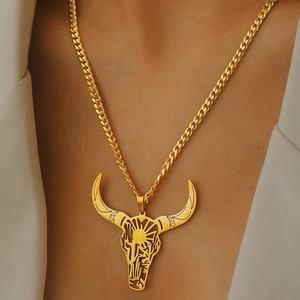 Collana con ciondolo teschio di toro dorato con catena cubana indossata su un abito beige
