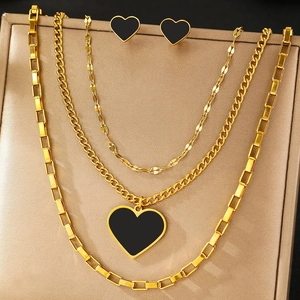 Layered gold heart necklace set with black enamel pendant and matching stud earrings