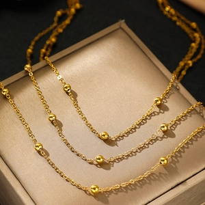 Bohemian multi-layer stainless steel necklace with gold beads and tassels on a jewelry box