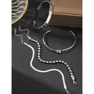 Polished silver heart pendant bracelet and sleek bangles set on black matte background