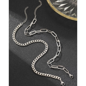 Set of two bohemian silver metal anklets with curb and paperclip chains on black surface