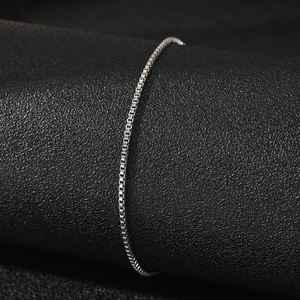 Élégante chaîne de cheville en acier inoxydable argenté pour femmes sur un support noir