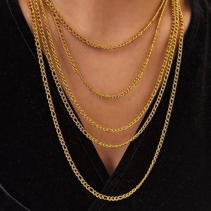 Polierte 18K Gold Figaro Halsketten in mehreren Lagen auf schwarzem Hintergrund