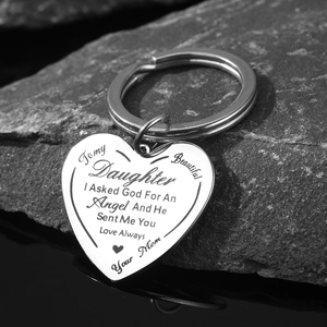 Stainless steel heart pendant keychain with engraved message on dark textured rock