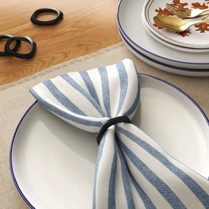 Detail of matte black irregular metal napkin rings on a modern dining table setting