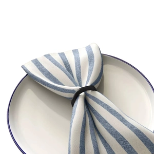 Irregular round metal napkin ring in dark finish on a white plate with blue striped linen