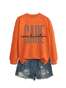 Detail of orange crewneck sweatshirt with CARE coordinator print and distressed denim shorts