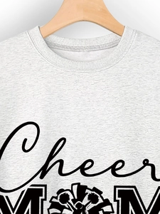 Détail du col côtelé et de l'imprimé Cheer MOM sur le tissu gris du sweat-shirt