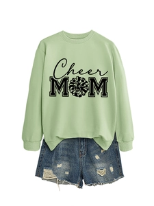 Détail du sweat vert clair Cheer MOM avec short en jean bleu effiloché sur fond blanc plat