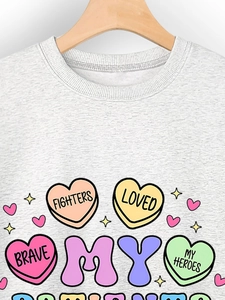 Detail of grey crewneck sweatshirt featuring colorful heart prints and bold typography