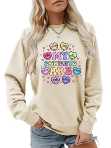 Detail of beige round neck sweatshirt with colorful heart prints and medical-themed text