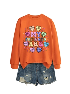 Detail of orange crewneck sweatshirt with colorful heart prints and denim shorts set