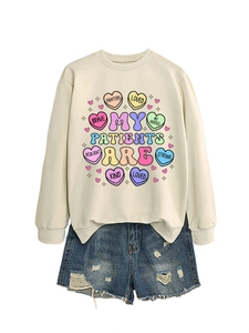 Detailed flat lay of a beige sweatshirt with inspirational heart graphics and denim shorts