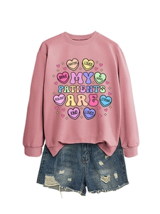 Flat lay of pink crewneck sweatshirt with heart print and distressed denim shorts