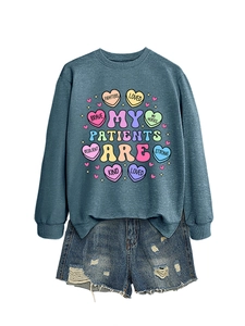 Flat lay of a teal crewneck sweatshirt with heart graphics and denim shorts set