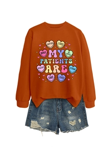 Detail of orange crewneck sweatshirt with colorful heart prints and positive text