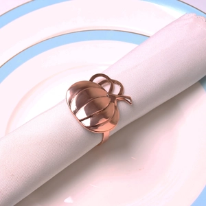 Detailed close-up of rose gold pumpkin napkin ring on a white cotton napkin and plate