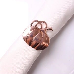 Detail of rose gold pumpkin napkin ring with realistic stem and vine on a white cloth