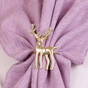 Detail shot of a matte gold reindeer napkin ring on a purple fabric for holiday decor