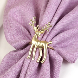 Close-up of matte gold reindeer napkin ring with detailed antlers on purple fabric
