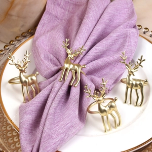 Set of four matte gold reindeer napkin rings on elegant plates for Christmas table decor