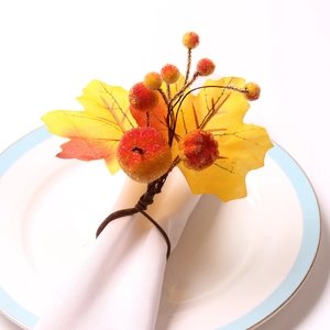 Autumn pumpkin and maple leaf napkin ring with orange berries on a white ceramic plate
