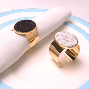Detail of elegant gold napkin rings with black and white marble stone on a white napkin