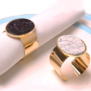 Detail of luxury gold napkin rings with black and white marble stone on a white napkin