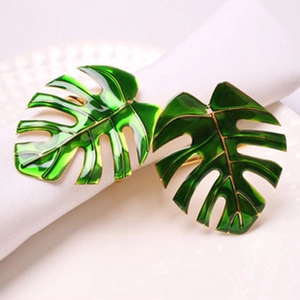 Detailed view of green monstera leaf napkin rings with golden edges on white linen