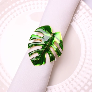 Macro detail of a green monstera leaf napkin ring with gold edges on a white table setting