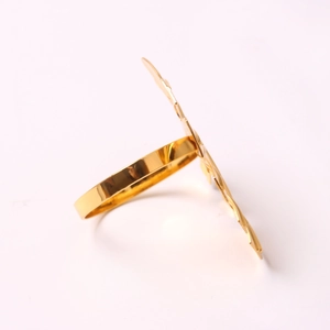 Macro side view of a gold monstera leaf napkin ring made of polished metal on white