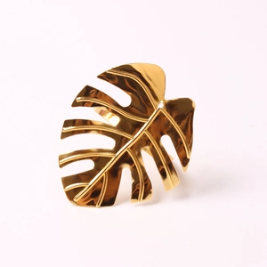 Macro view of golden monstera leaf napkin ring with polished mirror finish texture