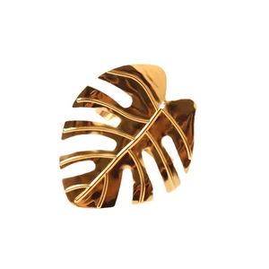 Golden monstera leaf napkin ring with polished metal finish on white background