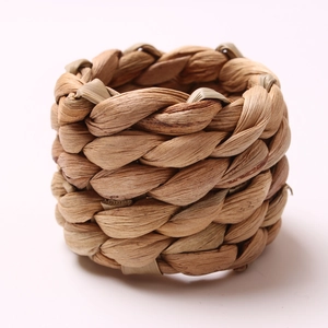 Handwoven water hyacinth napkin ring in natural straw color on a clean white background