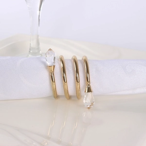 Detail of gold spiral napkin ring with crystal water drops on a white napkin