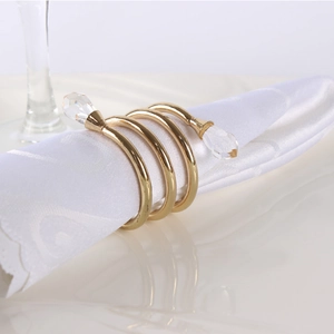 Elegant gold spiral napkin ring with crystal teardrops on a white textile napkin