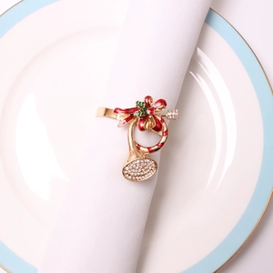 Gouden kersthoorn servetring met rode strik en strass-steentjes op wit tafelkleed
