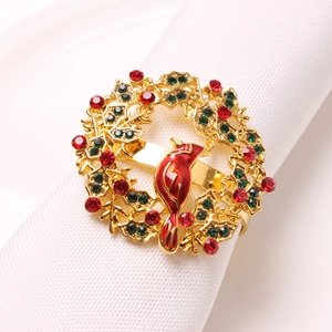 Golden Christmas napkin ring with cardinal bird and holly leaves on white fabric