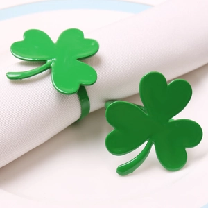Close-up of green clover napkin rings in metal finish on white napkins for table decor