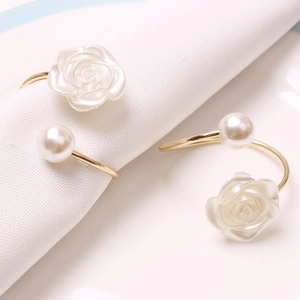 Elegant gold napkin ring featuring a carved rose and white pearl on white linen