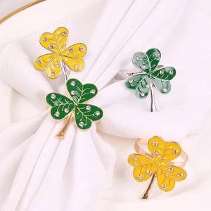 Detail of four heart-shaped shamrock napkin rings with enamel and crystals on white linen