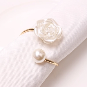 Elegant gold napkin ring with white rose flower and pearl on textured fabric