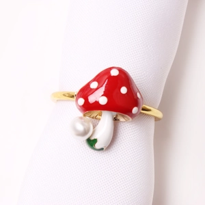 Red mushroom napkin ring with white dots and pearl detail on a white linen napkin