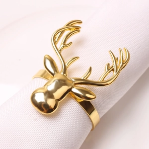 Close-up of polished gold reindeer head napkin ring on a white fabric napkin