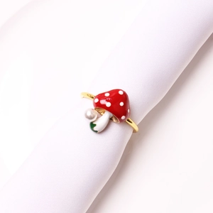 Red mushroom napkin ring with white dots and small pearl accent on a white linen napkin