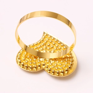 Golden heart-shaped napkin ring with beaded texture and polished metal finish for decor