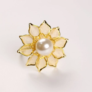 Macro detail of gold flower ring featuring a white pearl center and mesh petals